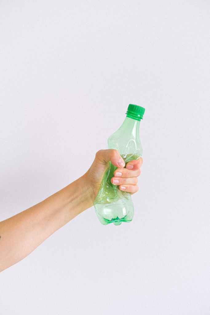 crop unrecognizable woman squashing plastic bottle