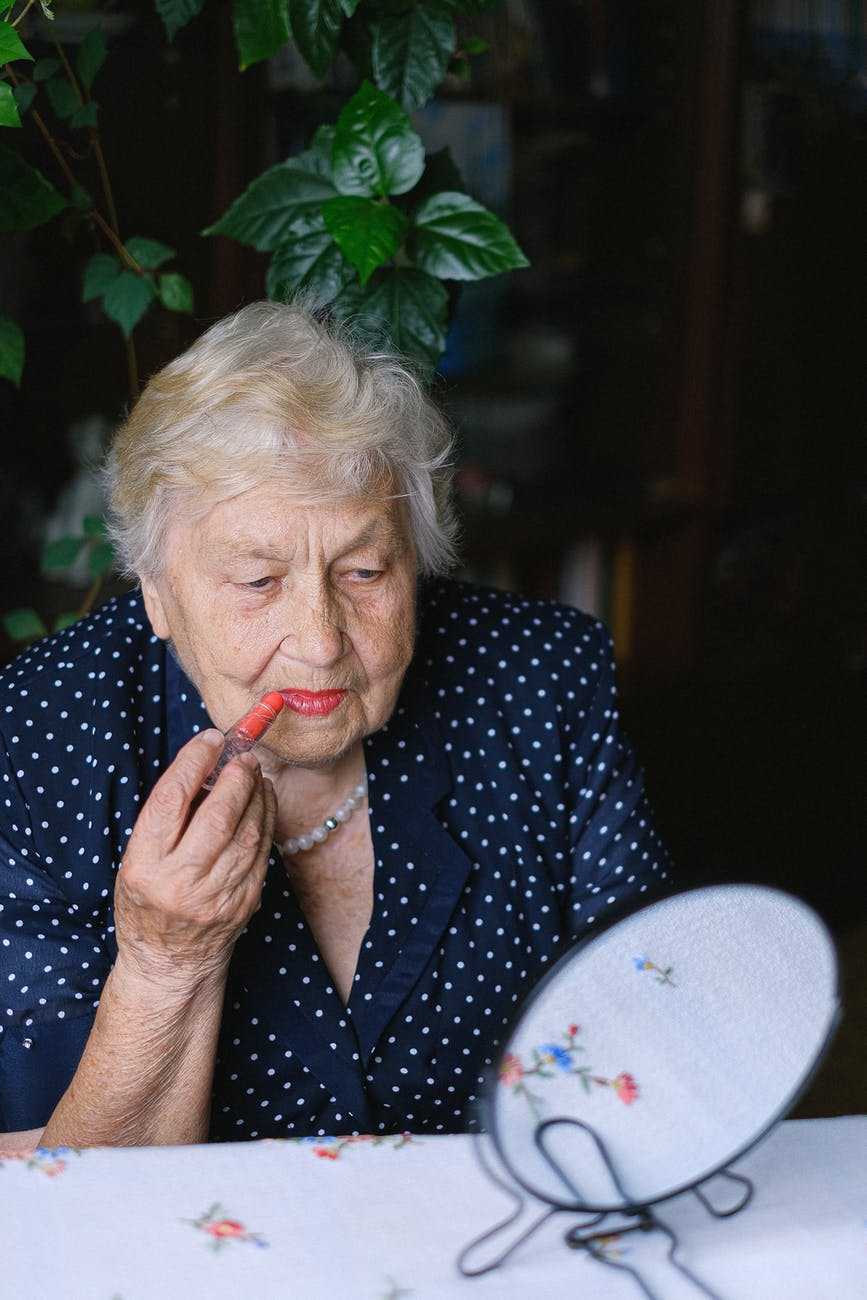old woman doing makeup in room