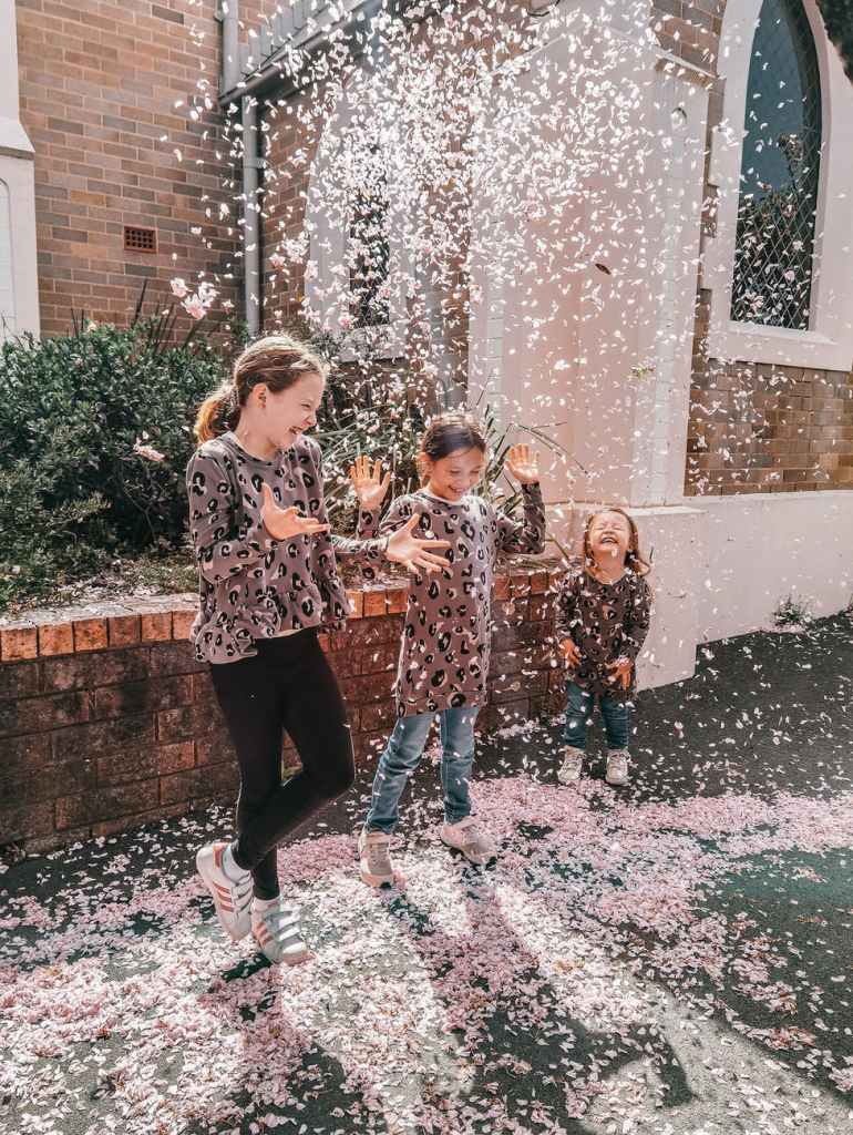 happy children playing with pink feathers in street near building